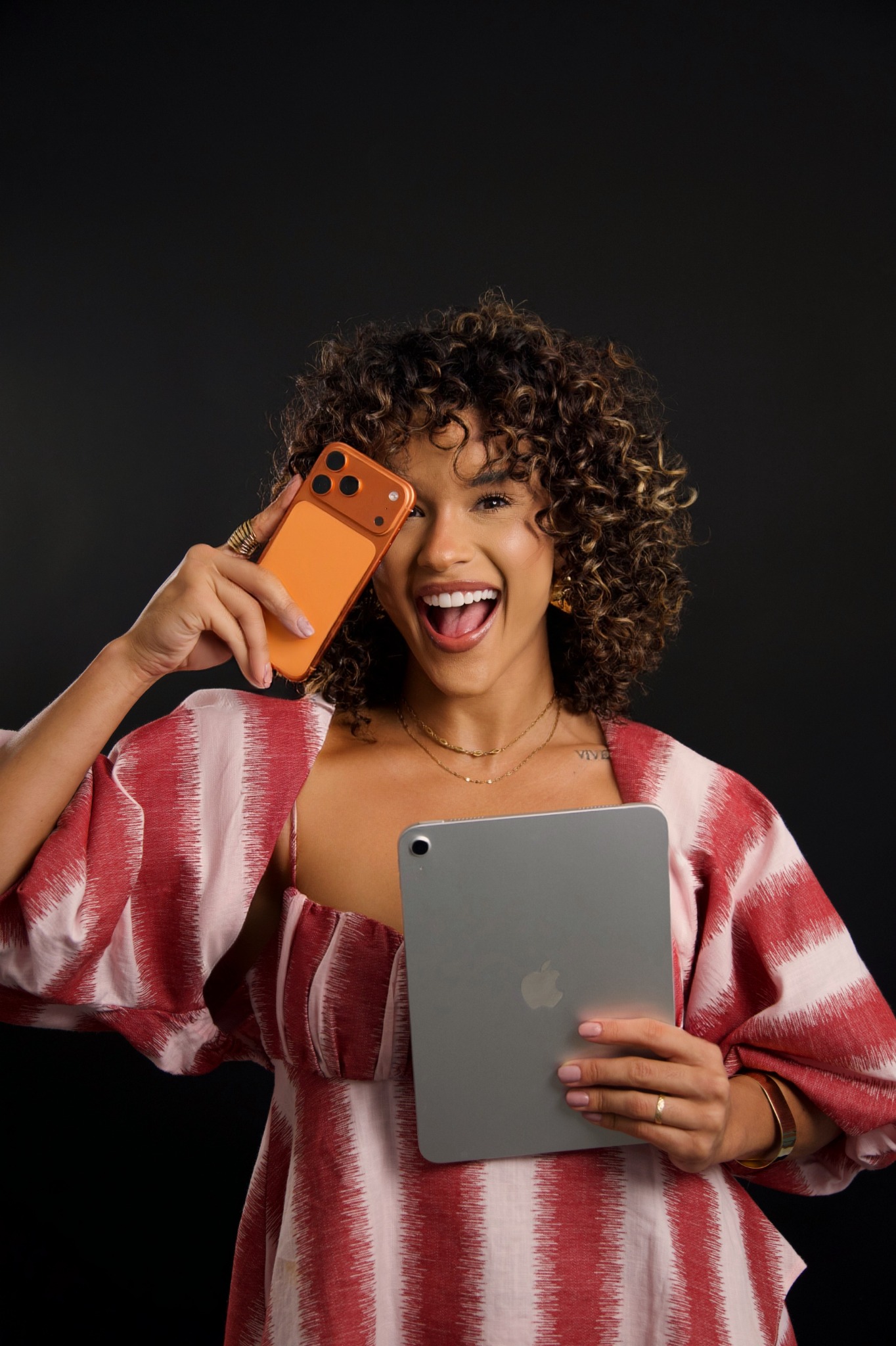 Iasmyne sorrindo com celular e tablet